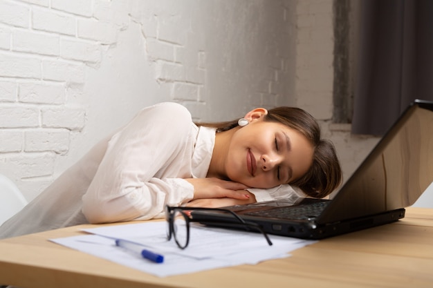 beautiful young female lies at the table with a laptop in the office