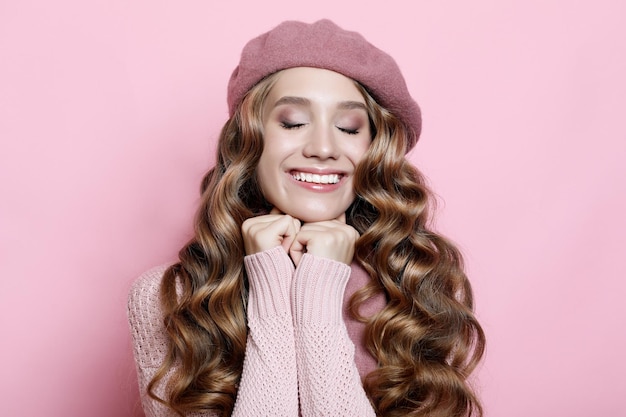 Beautiful young female model with long wavy hair wearing pink beret and scarf