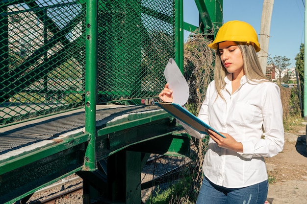 Beautiful young female supervisor wearing safety helmet reviewing reports