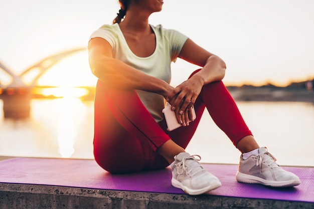 Beautiful young and fit woman in good shape exercise alone on\
city bridge street. she listens to music with headphones. beautiful\
sunset in background.