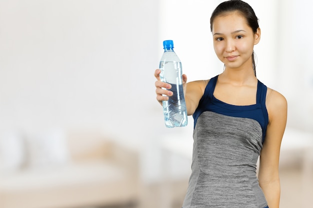 Beautiful young fitness woman with perfect body shape drinking fresh water