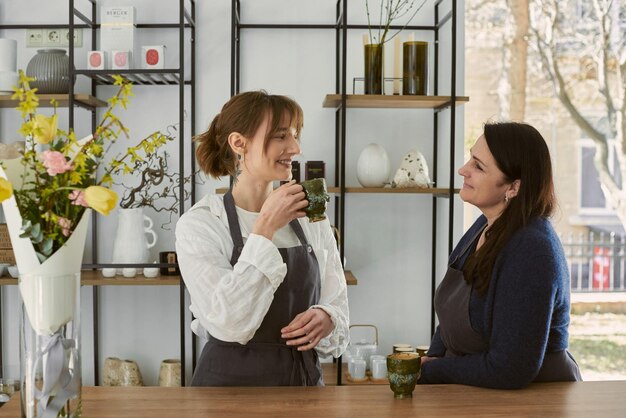 Beautiful young florist drinking coffee with his mother