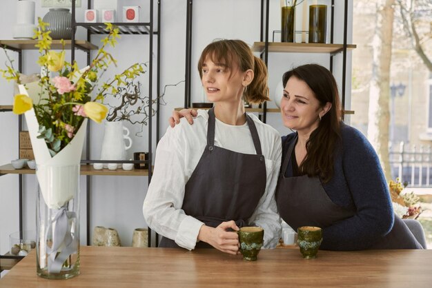 Beautiful young florist drinking coffee with his mother