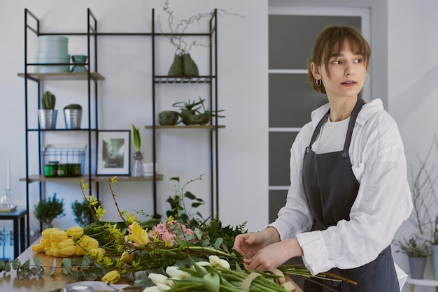 Beautiful young florist makes a bouquet