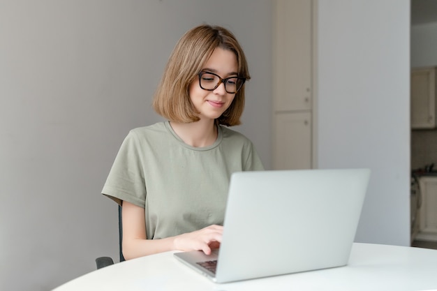 사진 집에 앉아 노트북 컴퓨터를 사용 하여 아름 다운 젊은 프리랜서 여자. 온라인 교육 개념