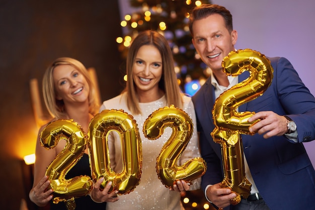 Beautiful young friends having fun at New Year's Eve Party holding numbers 2022