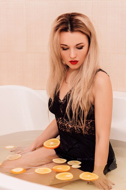 Beautiful young girl bathes in a bath with rose petals