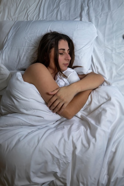 Beautiful young girl in bed with white bedding