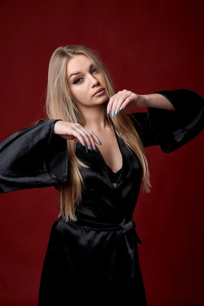 beautiful young girl in black lingerie and black satin robe on a dark background