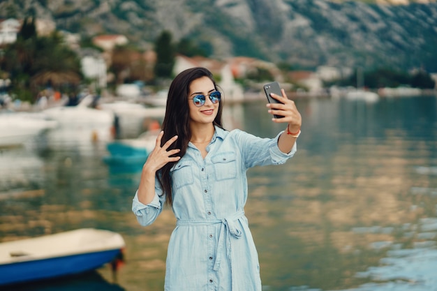 A beautiful young girl in a blue dress standing near water