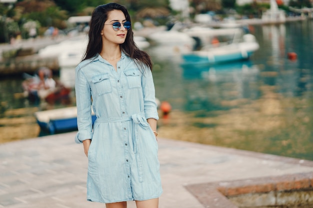 A beautiful young girl in a blue dress standing near water