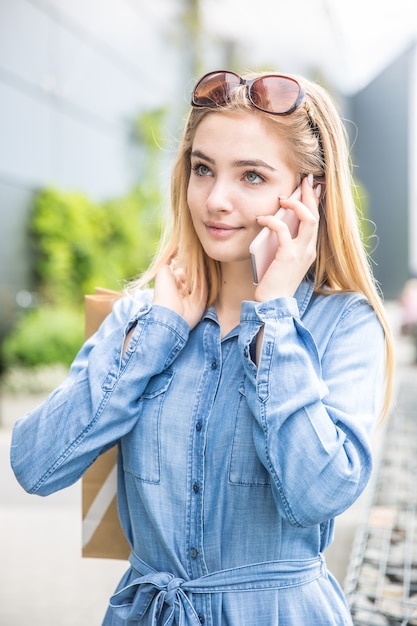 Beautiful young girl calling in shopping mall with baggs.