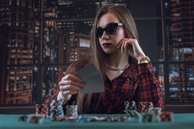 Beautiful young girl in dark glasses plays poker poker face