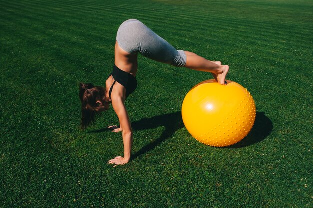 Beautiful young girl doing exercises with fit ball 