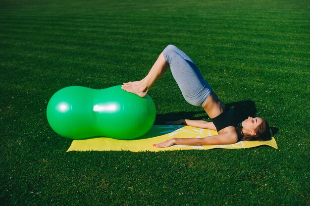 美しい若い女の子がfitballでエクササイズをしている