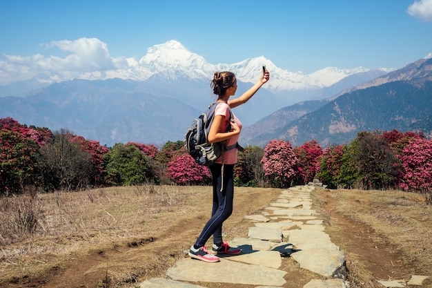아름답고 어린 소녀가 셀카를 하고 산에서 트레킹하면서 풍경을 촬영합니다. 산에서의 활동적인 레크리에이션과 관광의 개념. 네팔 히말라야 트레킹