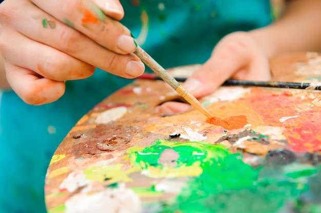 Beautiful young girl draws a picture paints on art lesson