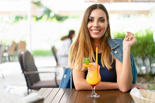 Una bella ragazza che beve un cocktail estivo esotica