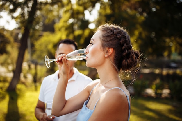 Beautiful young girl drinks champagne at a luxury wedding.