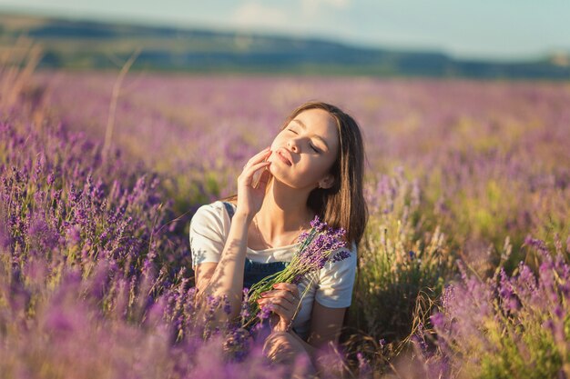 Bella ragazza che gode della luce solare in un giacimento della lavanda