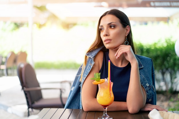 ヨーロッパの外観の美しい少女がエキゾチックな夏のカクテルを飲んでいます