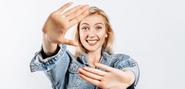 Beautiful young girl fooling around and pulling her hands forward on gray isolated background