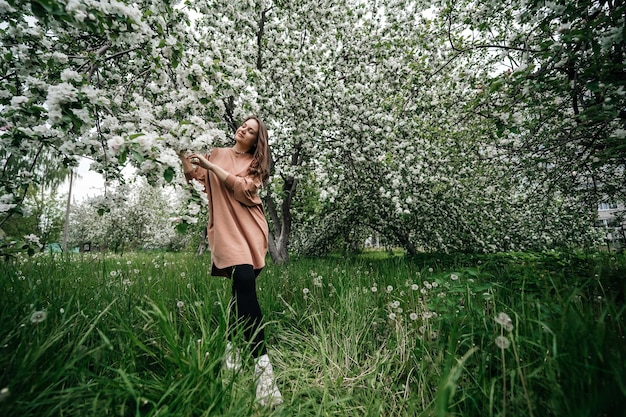 Foto bella ragazza nel giardino di alberi di mele in fiore persona