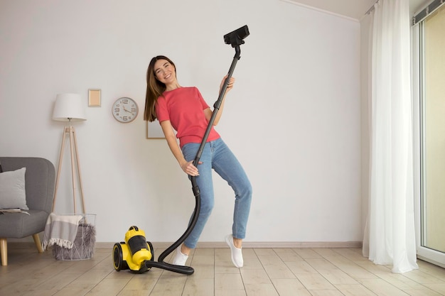 Beautiful young girl in a good mood makes house cleaning with a vacuum cleaner