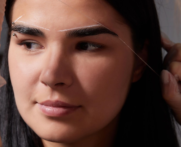 Photo beautiful young girl got correction of eyebrows in a beauty salon