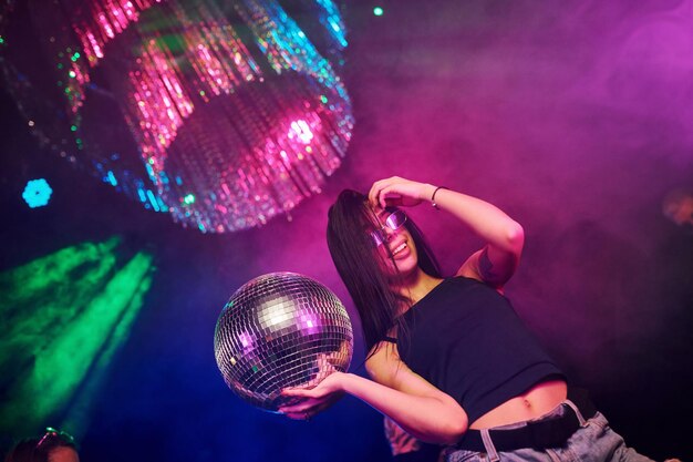 Beautiful young girl have fun dancing in the night club Holding party ball