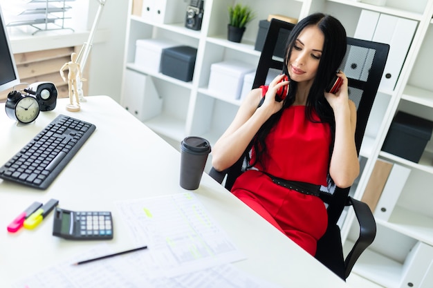 Beautiful young girl in headphones sits in the office at the table.