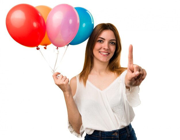 Beautiful young girl holding a balloon and counting one