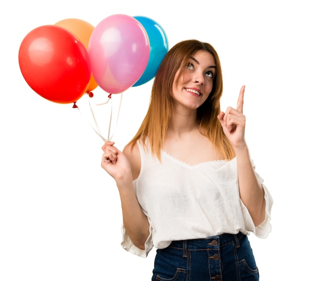 Beautiful young girl holding a balloon and pointing up