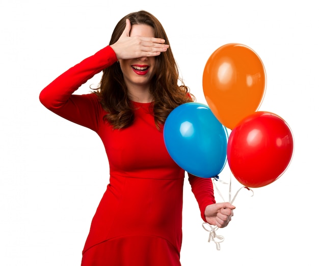 Beautiful young girl holding balloons and covering her eyes