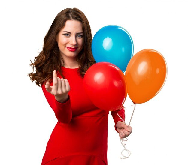 Beautiful young girl holding balloons and doing coming gesture