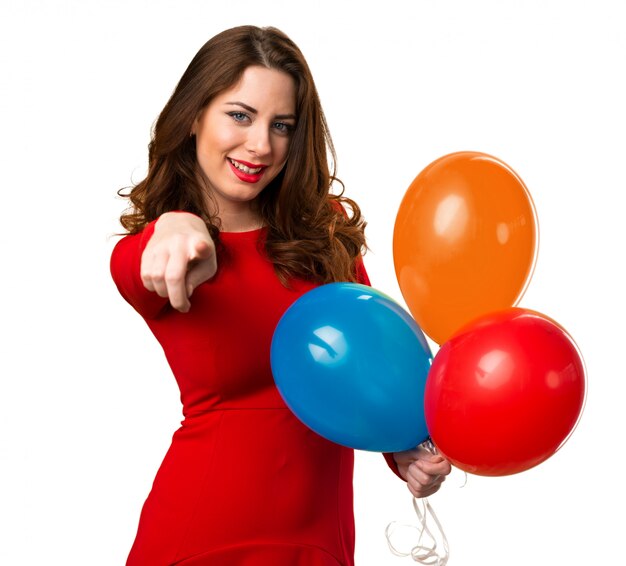 Beautiful young girl holding balloons and pointing to the front