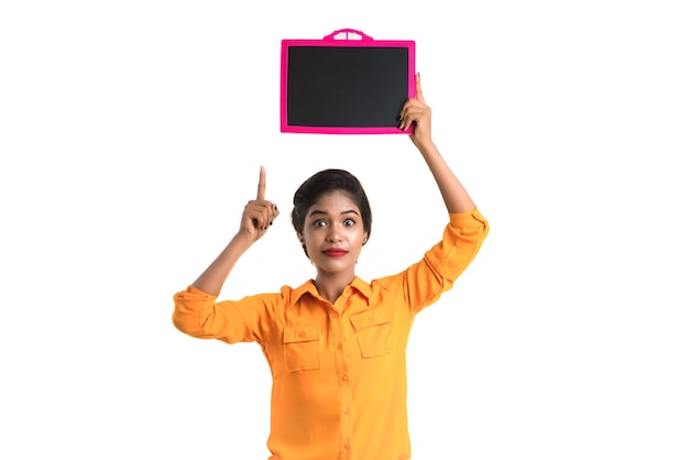 Beautiful young girl holding a chalkboard or slate, isolated over white background