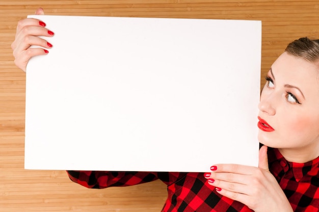 Photo beautiful young girl holding an empty white poster