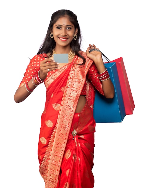 Красивая молодая девушка держит и позирует с сумками для покупок и кредитной или дебетовой картой на белом фоне