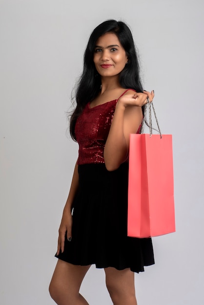 Beautiful young girl holding and posing with shopping bags on a grey
