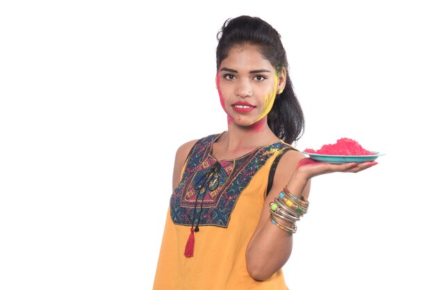 Beautiful young girl holding powdered color on a plate and enjoying colors on the occasion of the Holi festival.