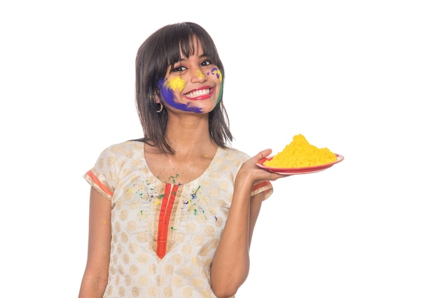 Красивая молодая девушка держит порошкообразный цвет в тарелке по случаю фестиваля Холи.