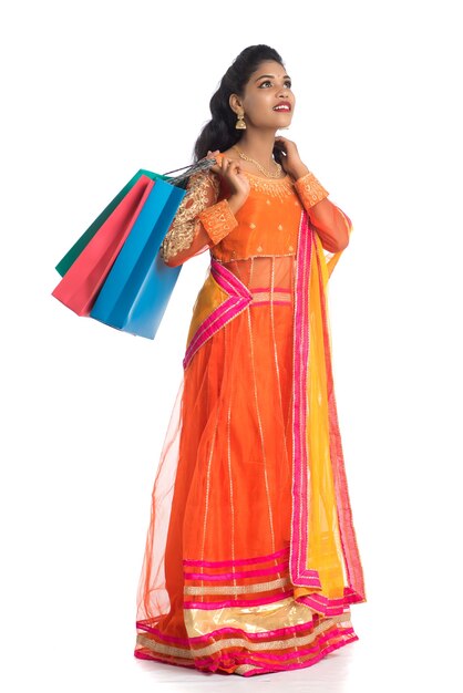 Beautiful young girl holding shopping bags while wearing traditional ethnic wear on white