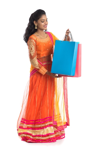 Beautiful young girl holding shopping bags while wearing traditional ethnic wear on white