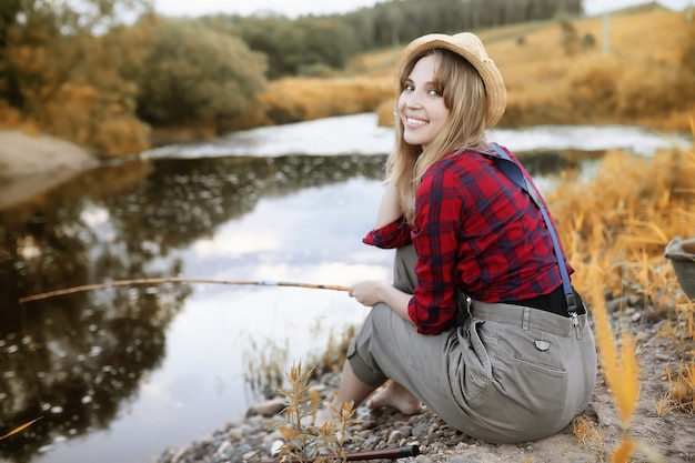 写真 釣り竿と川のそばの秋の美しい少女
