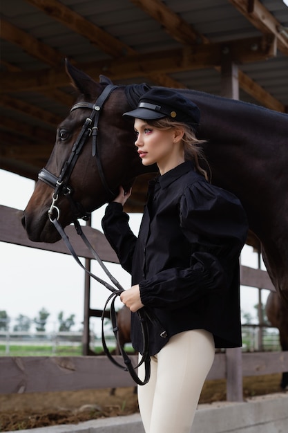 A beautiful young girl is holding a horse by the reins