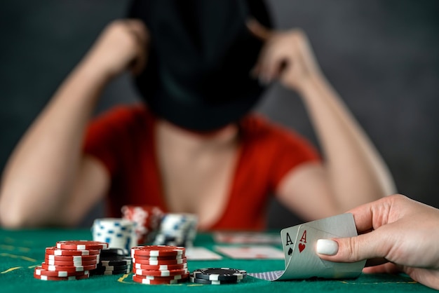 Beautiful young girl is sitting at a poker table with cards in her hands poker game of chance woman's hands hold poker cards