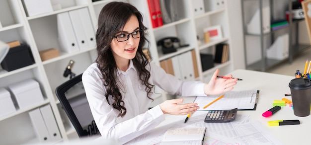 Photo beautiful young girl is sitting at the table in the office and is holding negotiations