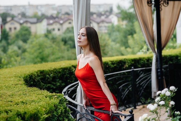 A beautiful young girl is standing on the veranda of a beautiful house.