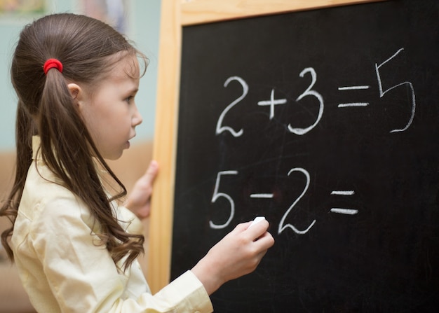 Beautiful young girl is teaching at home on blackboard